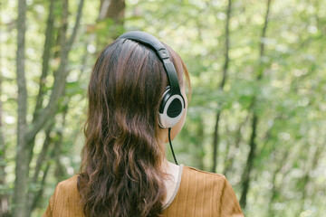 新緑の中で音楽を聴く女性　
ヘッドフォンで音楽を聴く女性