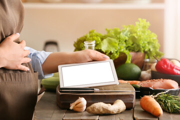 Pregnant woman using digital recipe book for cooking in kitchen, closeup