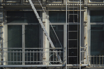 Fototapeta na wymiar Close up of grey and white city building windows with fire escape and bicycle in Manhattan, New York City