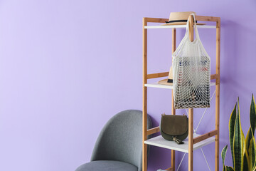 Shelving unit with accessories and chair near lilac wall