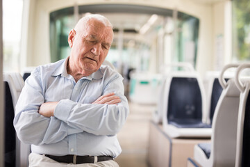 Old European gray haired man sitting in streetcar and sleeping.