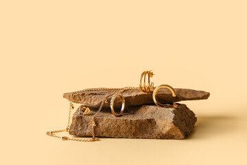 Granite stone with stylish jewelry on color background