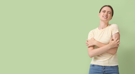 Young woman scratching herself on color background
