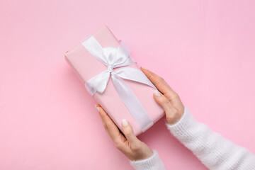 Woman holding gift box on pink background, closeup