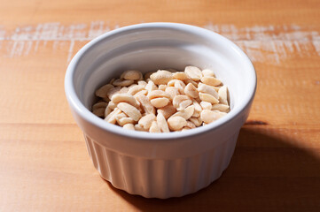 Close-up view of salted peanuts in ceramic container on wooden table
