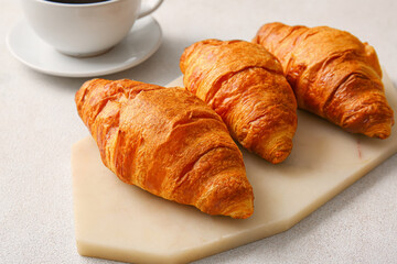 Board with delicious croissants on white background