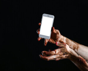 Hands of zombie with mobile phone on dark background