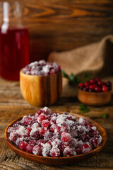 Plate with sugared cranberry on wooden background, closeup