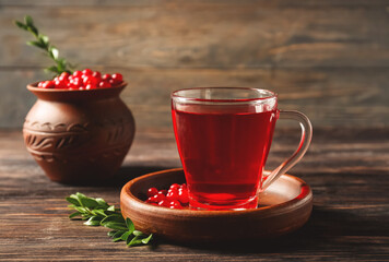 Glass cup of tasty lingonberry tea on wooden background