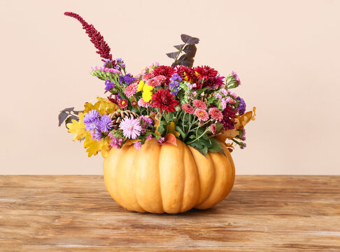 Beautiful autumn bouquet in pumpkin on table against light background