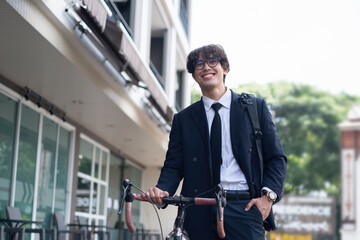 Handsome young asian businessman in suit have smiling with bicycle go to work at morning