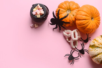 Halloween pumpkins with decor and candies on pink background