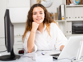 Portrait of young elegant confident female office worker in a company at a modern workplace