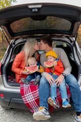 Young family had a picnic while sitting in the trunk of a car. Wellness concept.