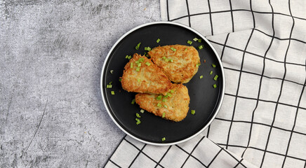 Traditional Hash brown potato fried pancakes on a round plate on a dark gray background. Top view, flat lay