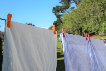 Clean washing handing on clothesline to dry with pegs outside