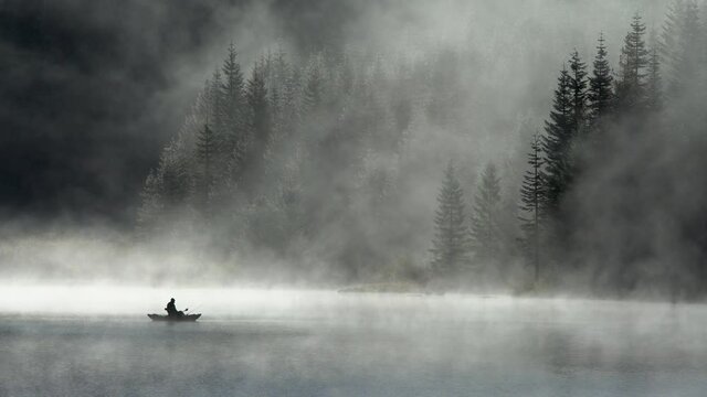 silhouette of man fishing on hemlock lake in the fog