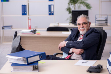 Old male employee sitting at workplace