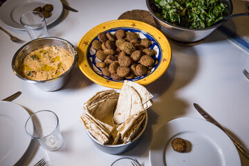 A bowl of falafel with hummus and salad and pita bread.