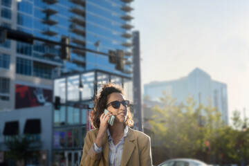 Latina woman talking on the phone while smiling in the street