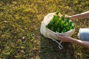 Woman unrecognizable with bag full of glass bottles for recycling