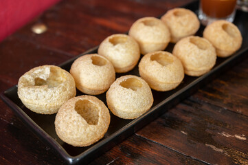 Popular Indian food named Pani puri served on table. Pani Puri is a combination of street food recipe made with small puri balls filled with spiced and mashed aloo and a specially made spiced water.