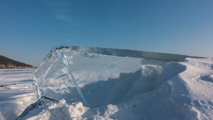 Transparent ice floe against the blue sky. Close-up. The glare of the sun on the edges. Snow on the...