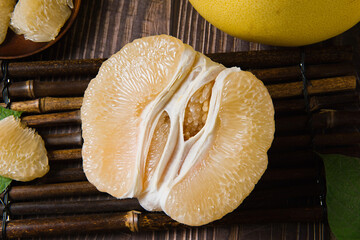 Ripe pomelo with pomelo slices on wood background