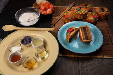Mid autumn festive colorful flower decorated moon cake making ingredients salted egg yolk flour honey syrup yam paste oil sugar chopsticks spoon plate bowl wooden bamboo tin glass