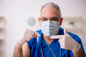 Old male doctor in vaccination concept