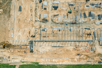 steel frame construction of modern hangar or factory. construction site with building materials and working machinery. aerial drone photo.