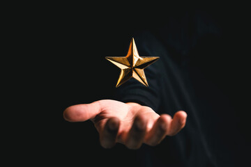golden star rating on hand in dark background