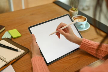 Close up view young female holding stylus pen and working with digital tablet.