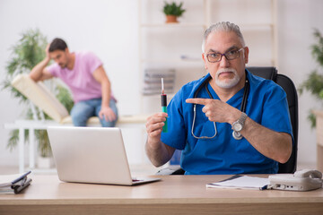 Old male doctor and young male patient in vaccination concept