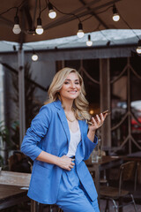 Beautiful woman businesswoman in a blue suit with a smartphone in her hands, teleworking. Soft selective focus.