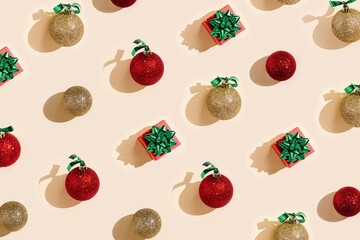 New Year holiday pattern with shiny red and golden Christmas balls and small gift box or present on pale pink background, minimal geometric layuot