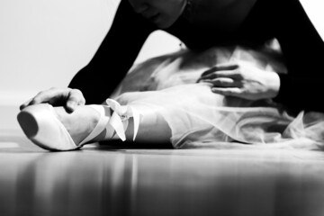 A ballerina in pointe is stretched before the performance. Black and white photo.
