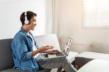 While holding a laptop and viewing a video call, a freelancer with headphones on explains. Attending clients and watching the video conference from home is made possible by wireless technology