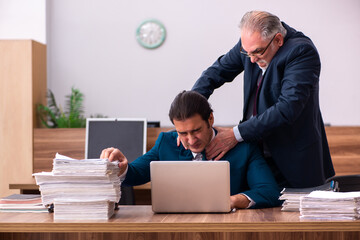 Old male employer and young male assistant in bullying concept