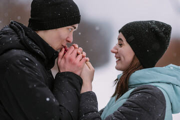 Portrait of couple of teenagers in winter. Boyfriend warming girlfriend's hands
