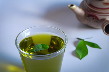 Hot green tea with tea leaves and vintage tea pot clay.