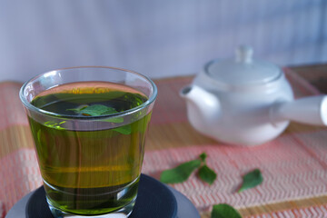 Fresh green tea with tea leaves and tea pot .