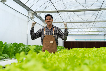 Happy young Asian farmer agronomist farmer smiling with hydroponic fresh green vegetables produce...