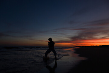 silueta de hombre practicando artes marciales al atardecer en la playa