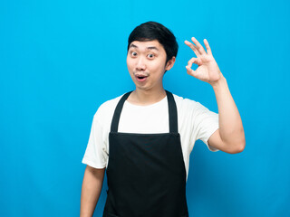 Asian man wearing apron black make hand ok blue background