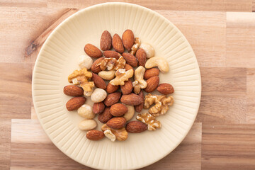 木のテーブルに置かれたミックスナッツ　
ウォールナット素材とナッツ