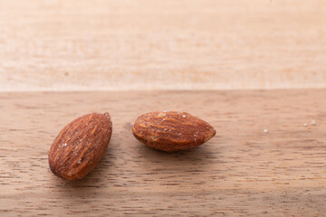 木のテーブルに置かれたアーモンド　
ウォールナット素材とナッツ