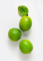 Three delicious limes with a leaf on a white background.