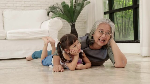 Asian grandmother and granddaughter lying on the floor together They both had fun and were happy. family concept happy home life