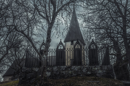 Row of black iron gravestones with an old church tower in the background